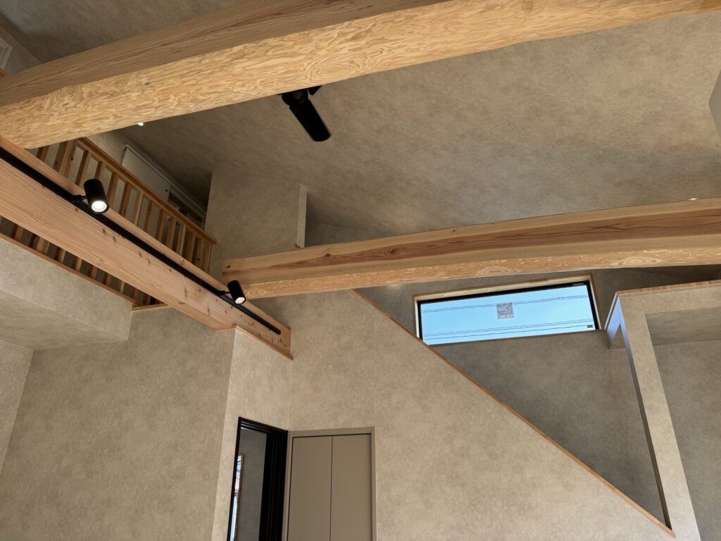 大きな梁が2本かかる吹き抜けリビングの天井と窓の様子