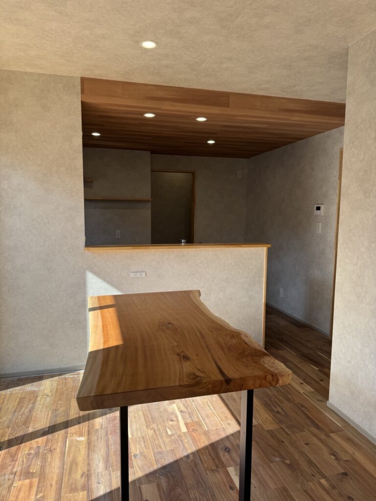 キッチンとダイニングをつなぐ折り下げ天井と一枚板テーブルのある空間