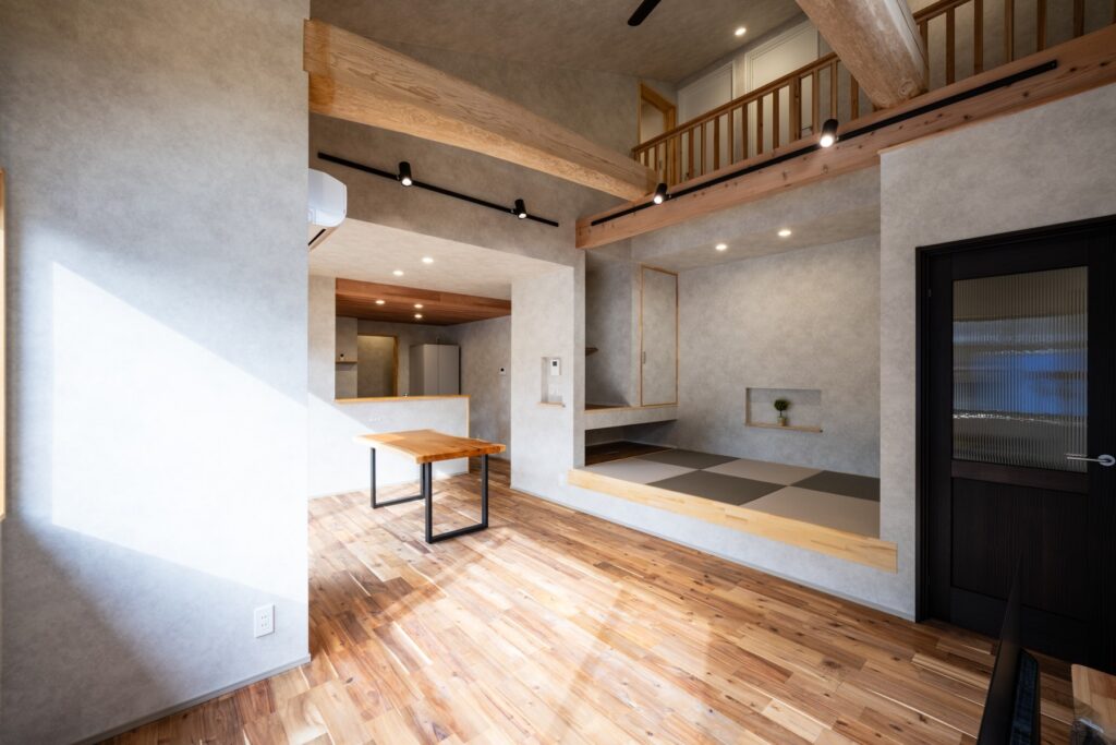 吹き抜けと大きな梁があるLDK全体の室内写真|畳スペースとつながる新築住宅