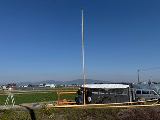 1本目の鯉のぼりの竿を人力で立てて設置中の様子