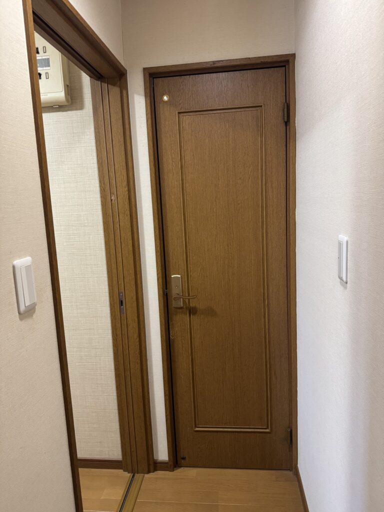 トイレドア交換前の様子｜木目調の既存ドアが設置された廊下